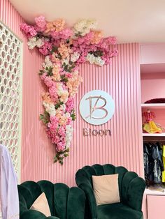 a pink room with two green chairs and flowers on the wall above it, along with a sign that reads b bloom