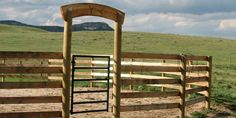 a wooden gate in the middle of a field