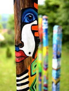 colorfully painted poles in the shape of totems are lined up on grass