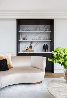 a living room filled with furniture and a white table topped with flowers in vases