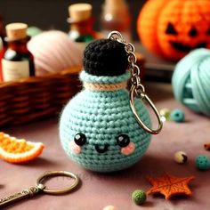 a crocheted keychain with a bottle on it and some pumpkins in the background