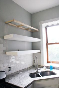 a kitchen with white tile and open shelving above the sink