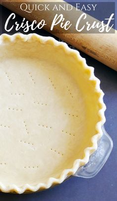 an uncooked pie crust next to a rolling pin on a blue counter top