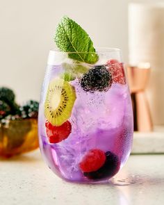 a glass filled with fruit and ice on top of a counter