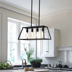 a kitchen with white cabinets and an island in front of a window that has light bulbs hanging from it