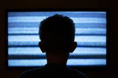 the back of a man's head in front of a television screen with sound waves on it