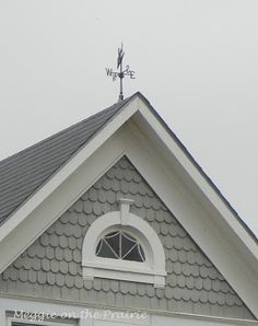 the top of a house with a weather vane on it's roof and an open window