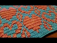 an orange and blue crocheted blanket sitting on top of a wooden table