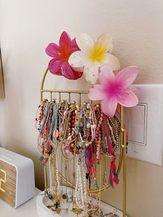 a bunch of bracelets and flowers on a gold stand next to an alarm clock