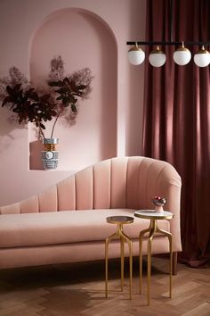 a living room with pink walls and two tables in front of the couch, along with potted plants