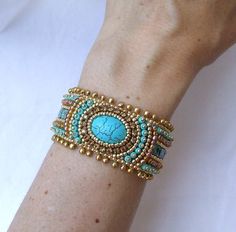 a woman's arm wearing a bracelet with turquoise stones and gold bead accents