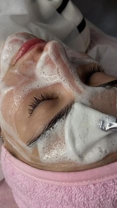 a woman laying down with her eyes closed while using a facial mask on her face