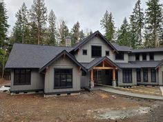 a large gray house in the woods with lots of windows and wood trimmings