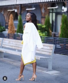 a woman is walking down the street with her coat over her shoulders and shoes on