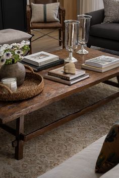 a coffee table with books, vases and candles on it in a living room