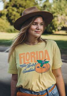 Ahh, nothing like fresh-squeezed sunshine. Breathe in the orange blossoms and beachy air with our new Florida tee. Inspired by vintage postcards and old souvenirs, this Floridian kitsch is sure to make you glow like the sun over the Keys. Unisex crew neck tee in Yellow. 100% combed and ring-spun cotton. Model wears size Large. Yellow T-shirt For Spring Vacation, Orange Short Sleeve Top For Beach Season, Orange Relaxed Fit T-shirt For Beach, Orange Letter Print T-shirt For Spring, Orange Graphic Print T-shirt For Summer, Casual Orange Tops For Vacation, Orange Relaxed Fit Top For Beach, Fun Orange T-shirt For Spring, Retro Orange T-shirt For Spring