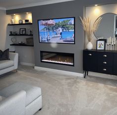 a living room filled with furniture and a flat screen tv mounted on the wall above a fireplace