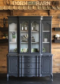 an old china cabinet painted in dark gray with white trim and glass doors that have the words born to be barn written on it