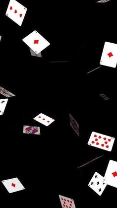 several playing cards are flying in the air on a black background with red and white dots