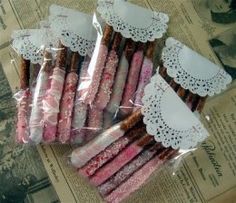 some pink and white candy sticks wrapped in cellophane with lacy doily on them