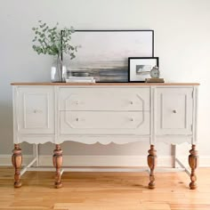 a white dresser sitting on top of a hard wood floor next to a vase filled with flowers