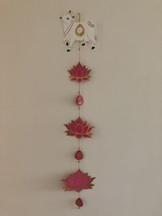 a pink and white clock with flowers on it's sides, hanging from the wall