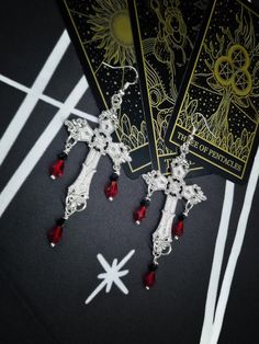 Our beautiful handmade Dark Lady Vampire  Gothic Cross Dangle Earrings are statement earrings which are sure to get you  noticed  they  feature a beautiful silver toned cross design with elegant red gem drops  a choice of earring style to customize to your requirement 🩸 All our Jewelry comes nicely packaged in a organza gift bag with cute stickers  All parcels come packaged in an fsc approved parcel and all packaging is fully recyclable ♻ 𝙋𝙧𝙤𝙙𝙪𝙘𝙩 𝙄𝙣𝙛𝙤𝙢𝙖𝙩𝙞𝙤𝙣 🔸Huggy Hoops Or 925 Silver Cross Jewelry For Halloween, Gothic Dangle Earrings For Festival, Silver Gothic Plug Earrings For Festival, Witchy Dangle Earrings For Festival, Gothic Sterling Silver Plug Earrings As Gift, Handmade Gothic Earrings For Festival, Handmade Gothic Sterling Silver Plug Earrings, Gothic Silver Dangle Earrings, Gothic Silver Pierced Earrings