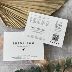 two thank you cards sitting next to each other on top of a table with green leaves