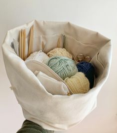 a person holding a bag full of yarn and knitting needles