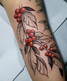 a tattoo with berries and leaves on the arm, done by an artist in progress