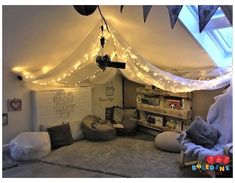 a bedroom with lights strung from the ceiling and pillows on the floor in front of it