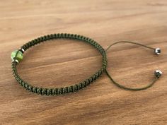 a green string bracelet sitting on top of a wooden table