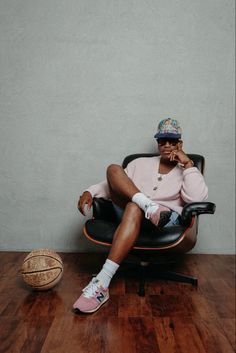 a man sitting in an office chair with his foot on the floor next to a basketball