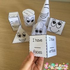 a person holding up some paper cones with faces on them and the words i have faces