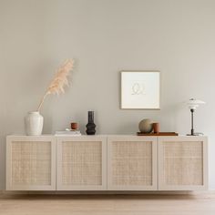 a white cabinet with two vases and a feather on top in a living room