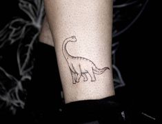 a small dinosaur tattoo on the arm