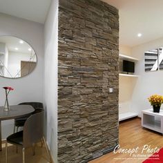 a living room and dining area with stone wall in the corner, wood flooring