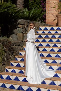 a woman in a white dress is standing on some blue and white steps with her hand on her hip