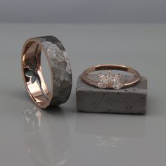 two wedding rings sitting next to each other on top of a stone block with a diamond in the middle