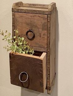 an old wooden box with a ring on it is holding a planter that has been placed in the drawer