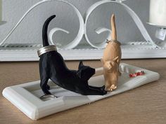 two black cats playing with each other on a white tray in front of a mirror