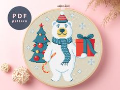 a cross stitch pattern with a polar bear holding a christmas tree and presents on it