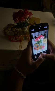 a person holding up a cell phone with flowers on it