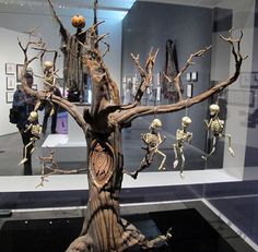 a display case with skeletons and tree branches in the shape of human figures on it