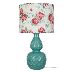 a green lamp with red flowers on it and a white lampshade behind it