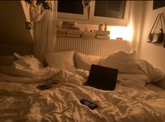 an open laptop computer sitting on top of a bed covered in white sheets and blankets