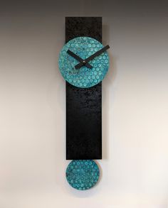 a black and blue clock hanging from the side of a wall