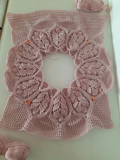 a crocheted doily with two balls of yarn next to it on a table