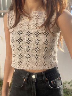 a close up of a person wearing a top with crocheted designs on it