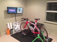 there is a bike that is in the room with a fan on it and a television